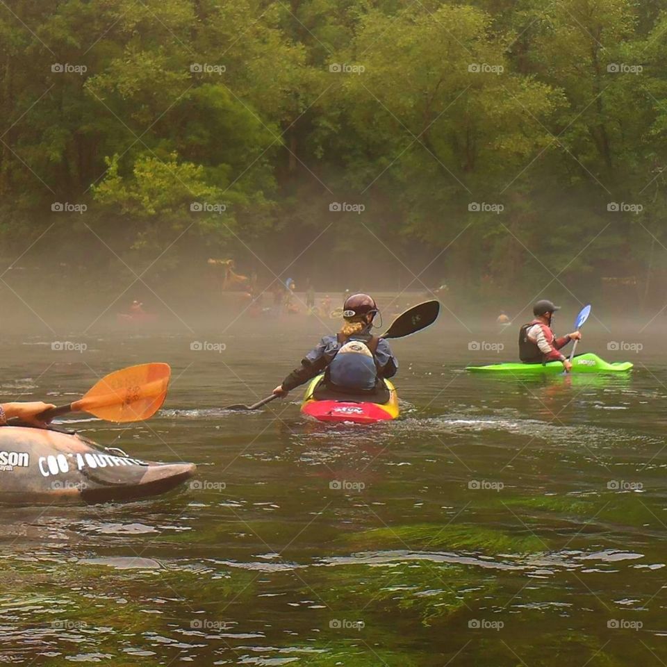Colorful whitewater kayakers paddling on a Misty morning on the Hiwassee River