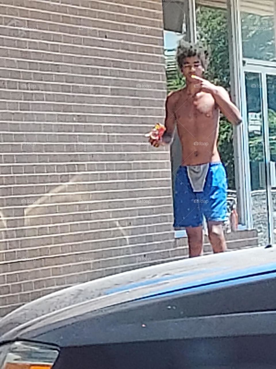 homeless man trying to stay cool as possible as he waits for the doors to open for the meal.
