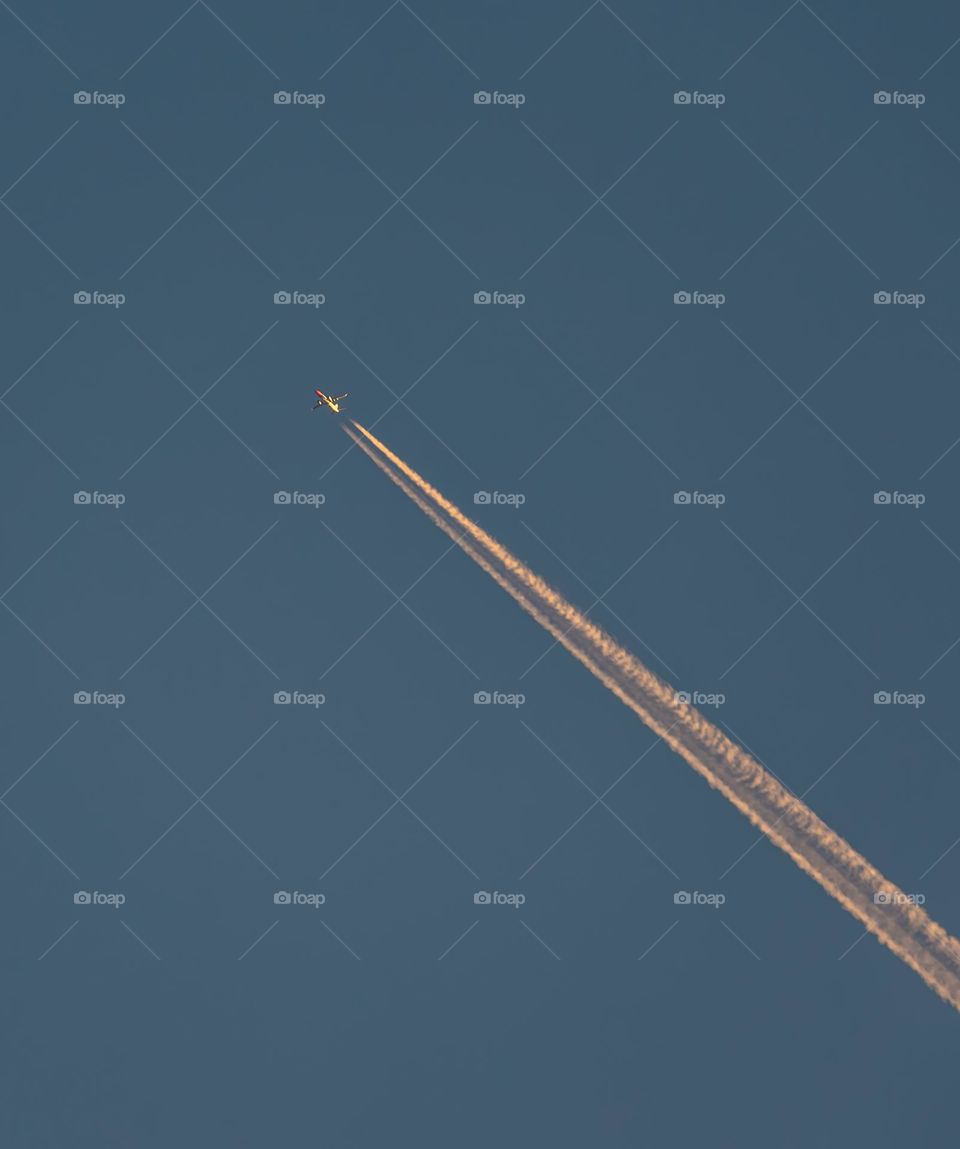 An airplane flying at dawn with a trail of engines