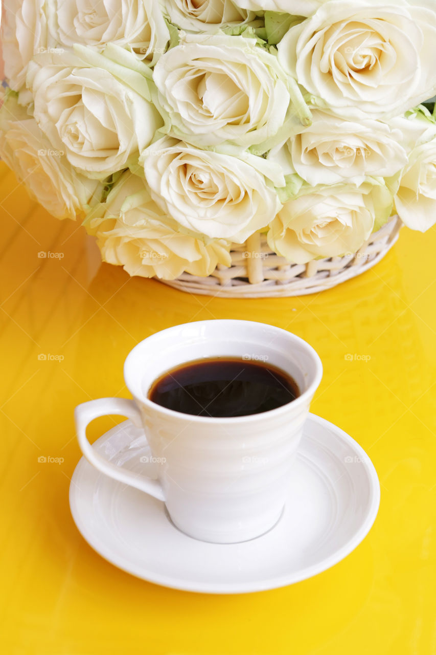 Close-up of black coffee and white roses on yellow table. Good morning!