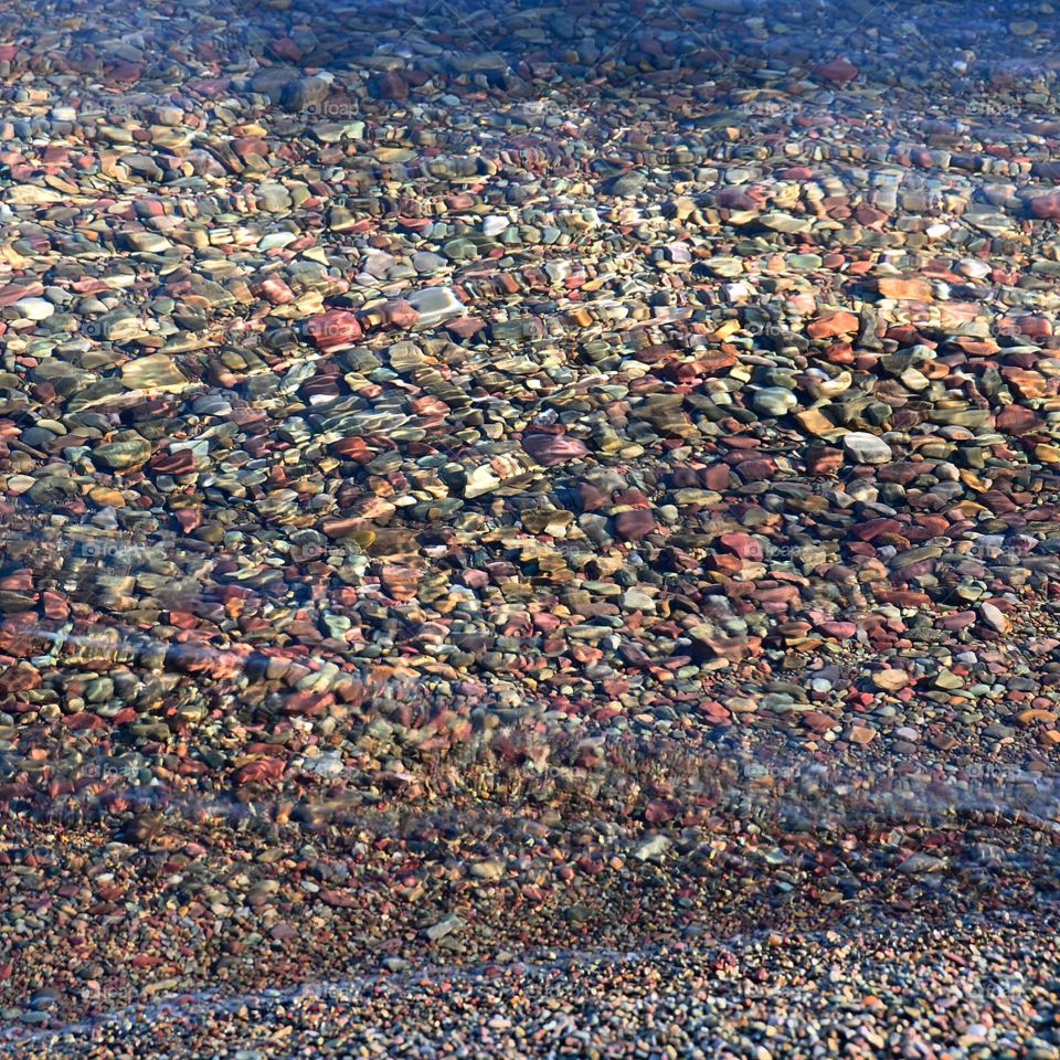 Colorful river stones under the water along the shore of Lake McDonald in Glacier National Park 
