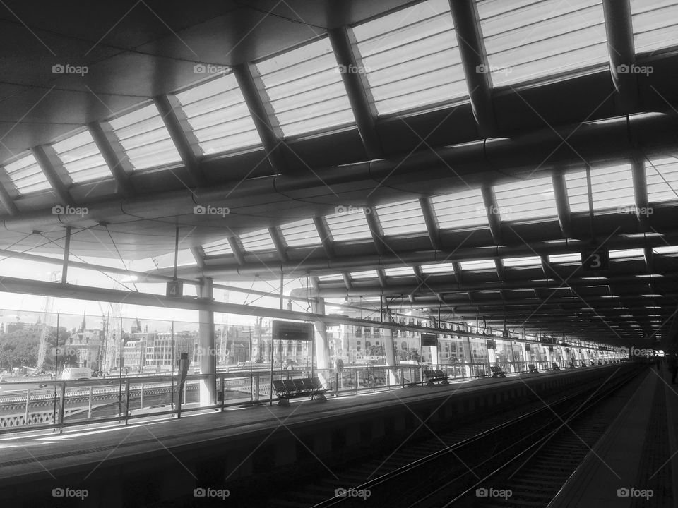 Platforms and roof of Blackfriars Station, London, spanning the River Thames, in monochrome
