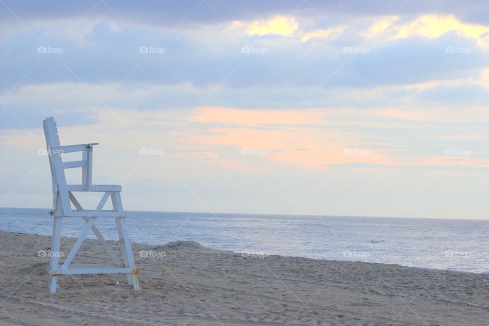 An empty lifeguard chair on the beach at dawn