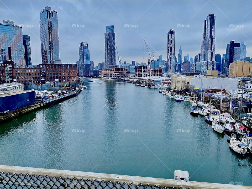 A wonderful panoramic view of the “East River”, an offshoot of the “Atlantic Ocean” at “Newtown Creek”, an inlet of the E River seen from the “Pulaski Bridge”. The skyline of both “Manhattan” and LIC is in the distance. 2023. Hypnotic Productions