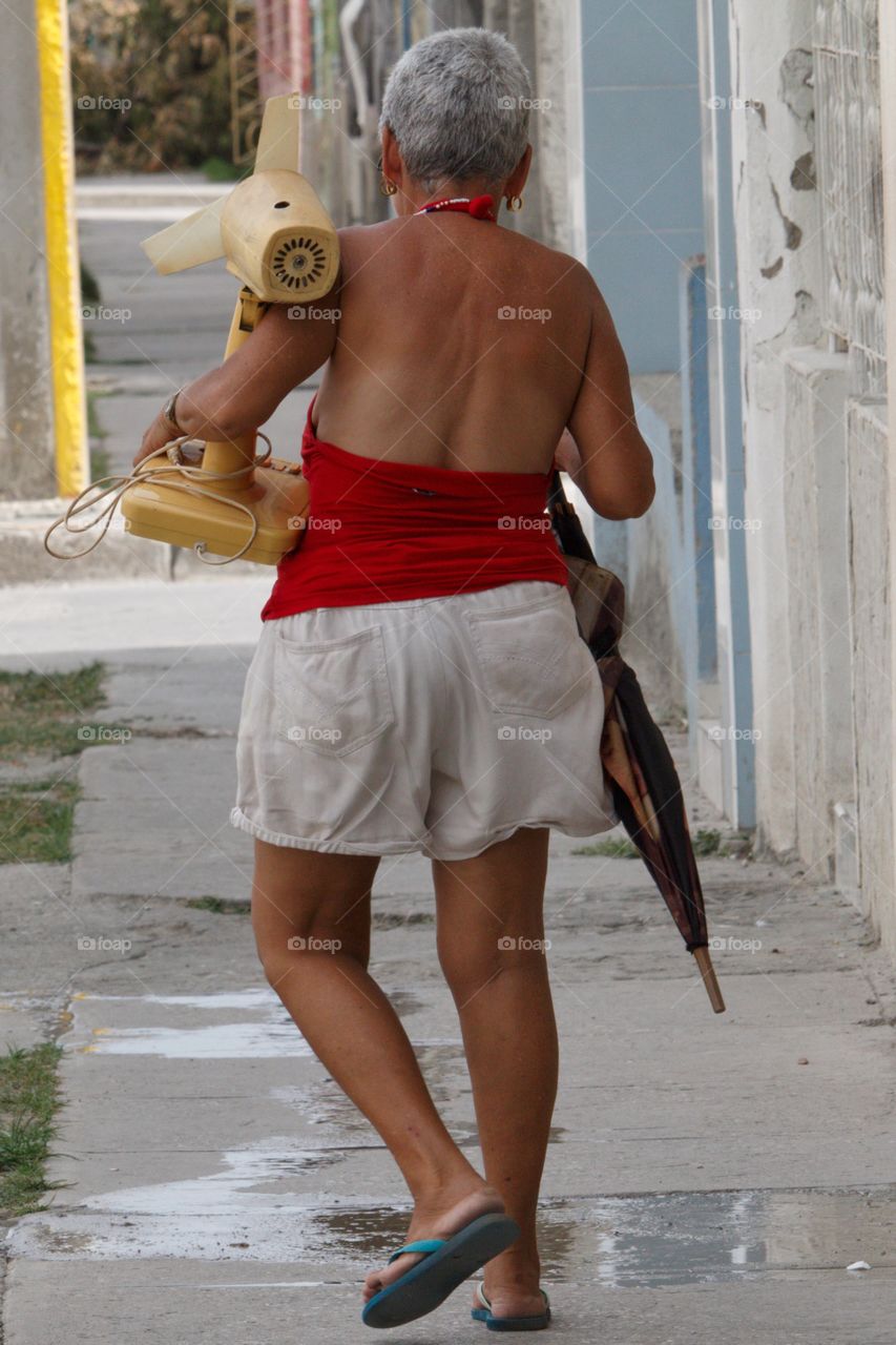 Cuban People.Woman carrying soviet vintage table fan in Guantanamo