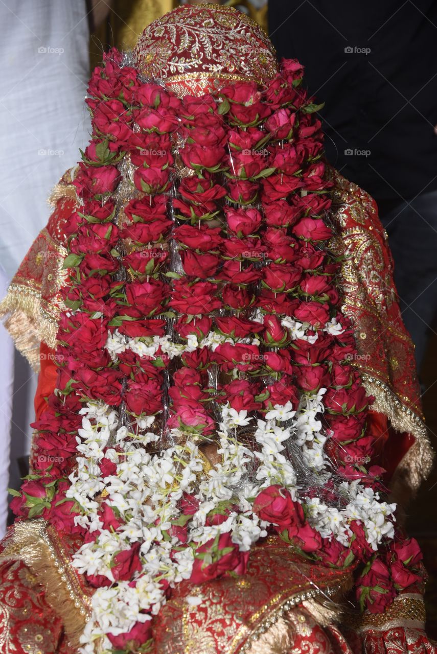 This is called Sehra used in Indian marriages made of red roses and other flowers