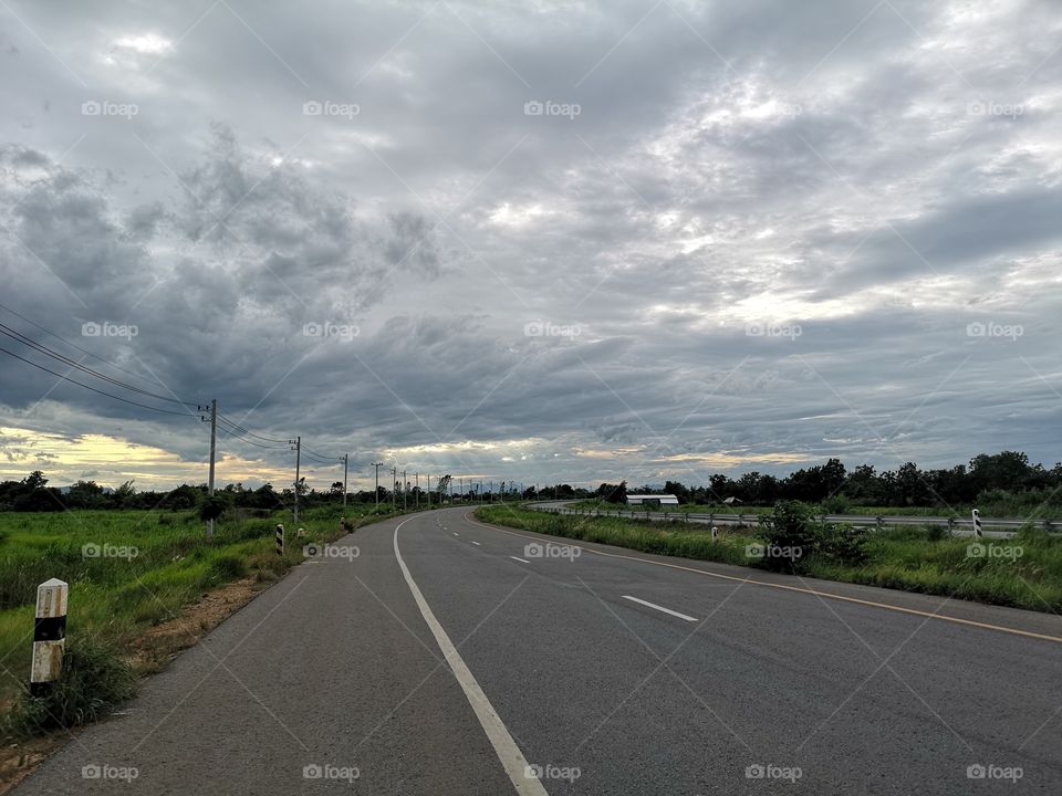 Road with clouds sky and natural views on both sides.