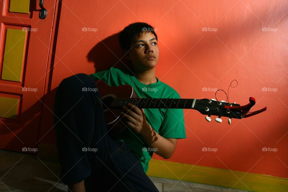 young asian teen playing guitar in a living room