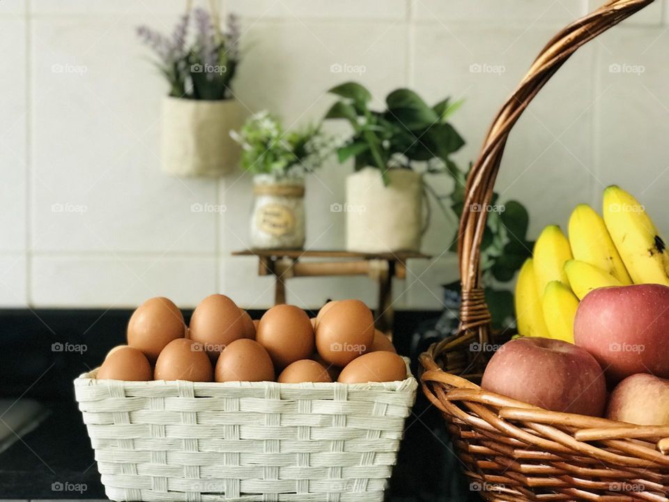 A basket full of eggs and colourful fruits in bamboo basket in that yellow banana looks so colourful 