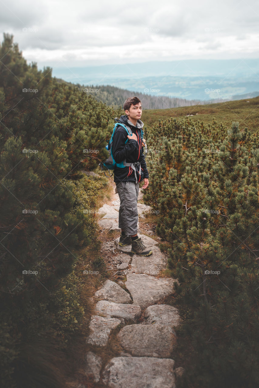 Boy with backpack standing among the dwarf pines during the trekking in The Tatra Mountains