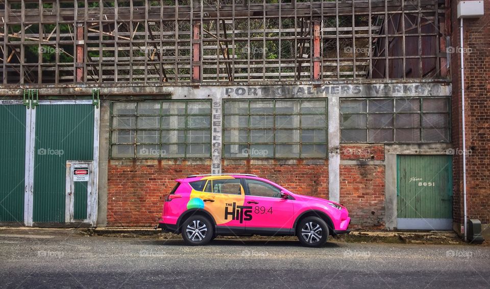 New car with advertising parked in front of old warehouse building