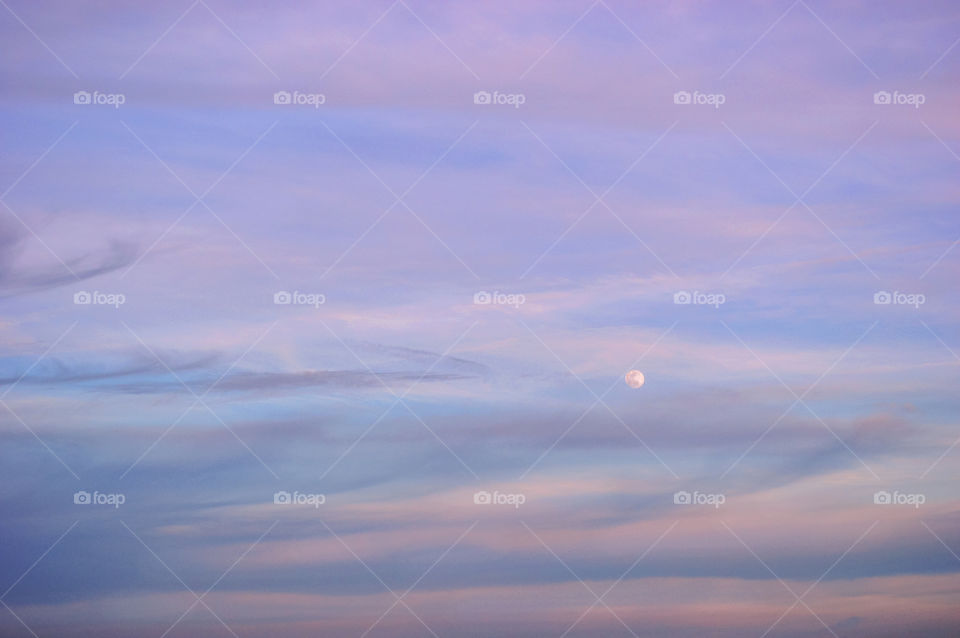 Colorful sunset sky of blue & purple & pink colors with the moon with clouds 