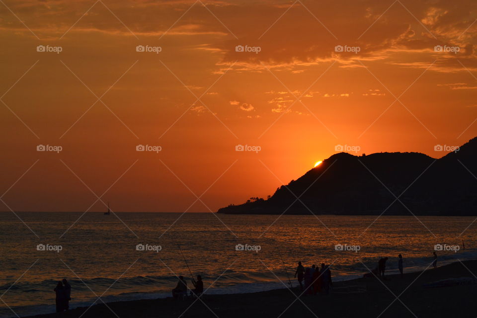 sunsetting over fishermen on the beach