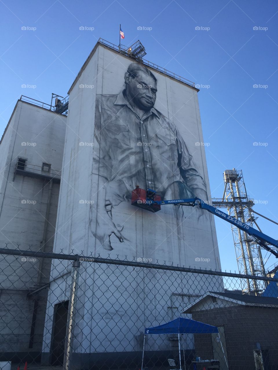 Mural artist at work creating portrait on a grain elevator in Fort Smith, Arkansas. 