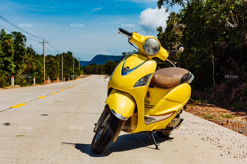 yellow moped stands on the road