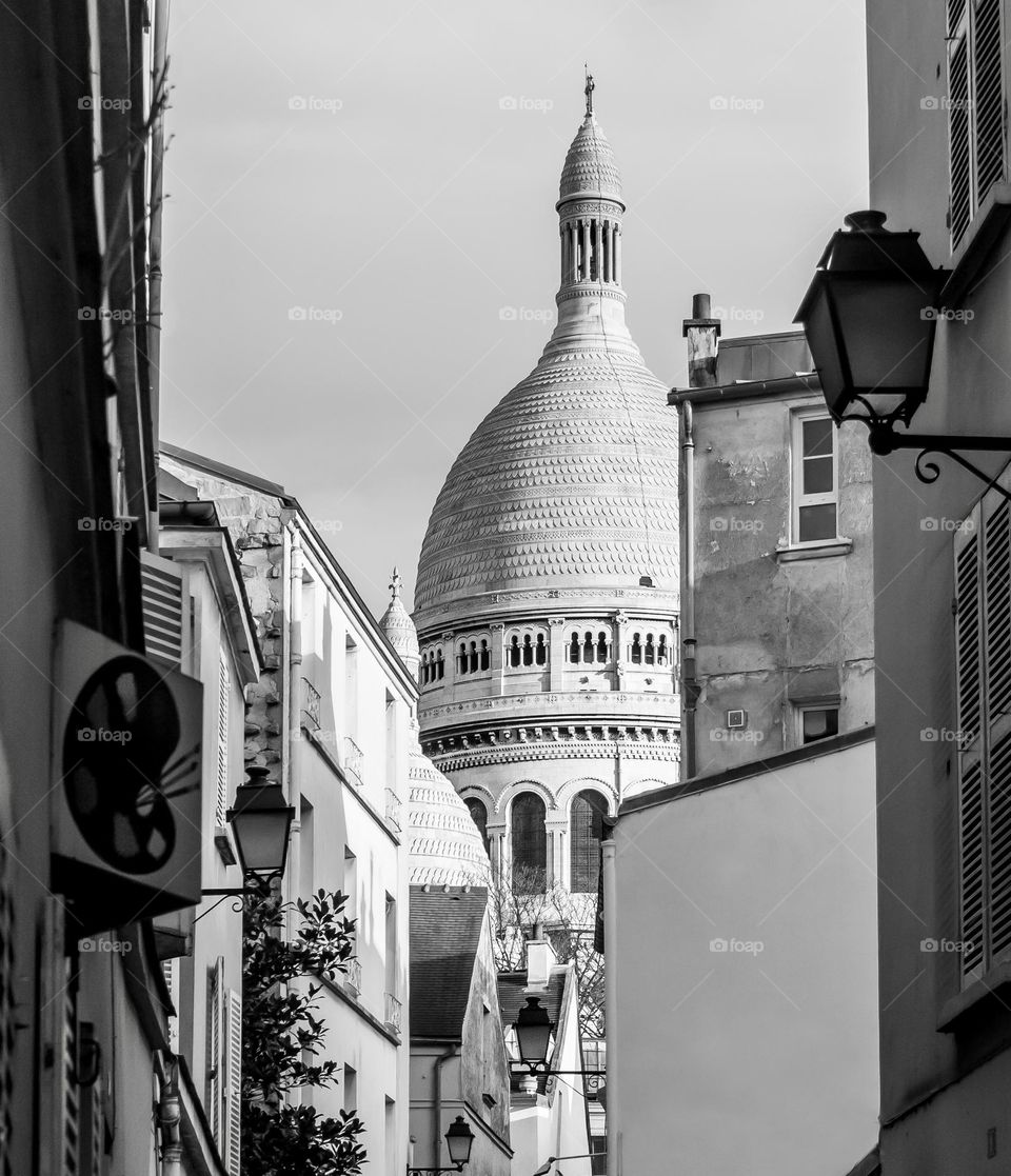 Along a narrow street in Monmartre, a domed tower of the Sacré Coeur can be glimpsed 