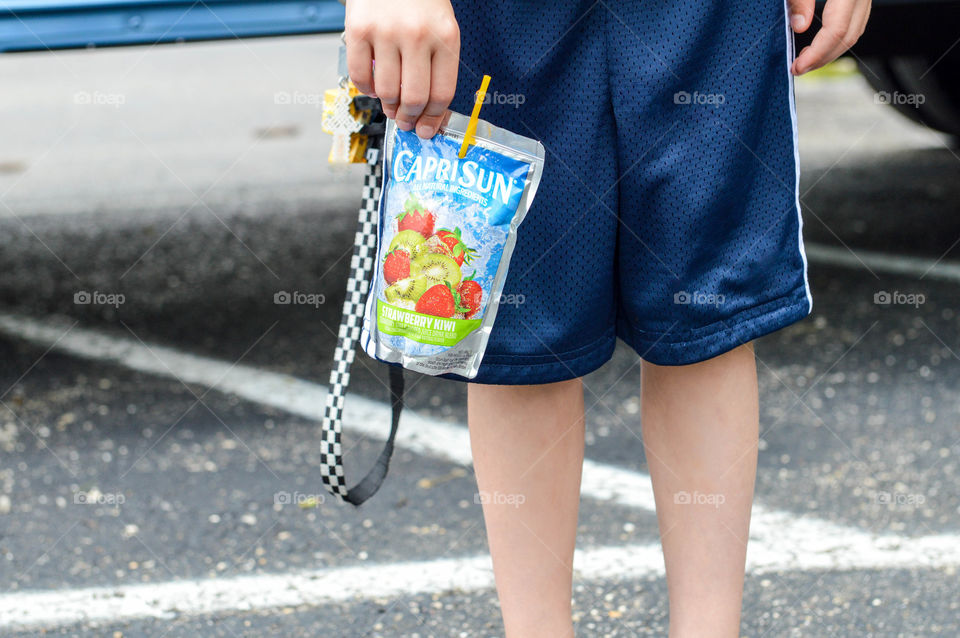 Young boy holding a drink pouch at his side at school
