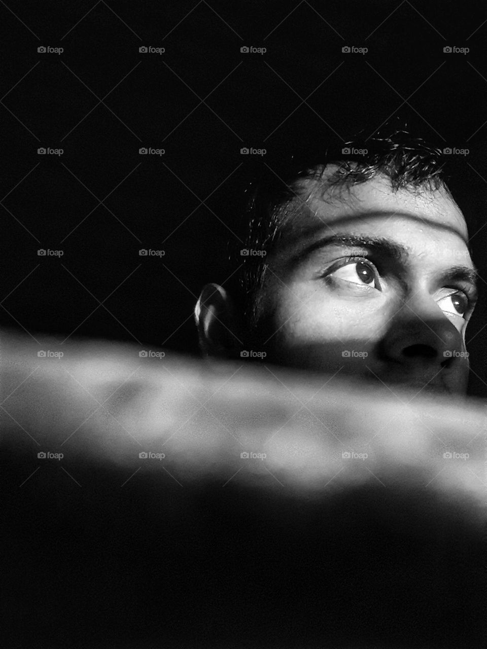 A black and white photo taken at night from behind the shadows