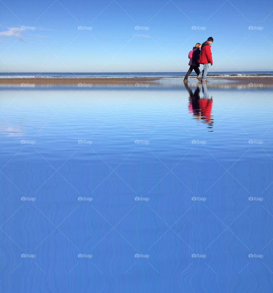 Two people strolling along the beach 