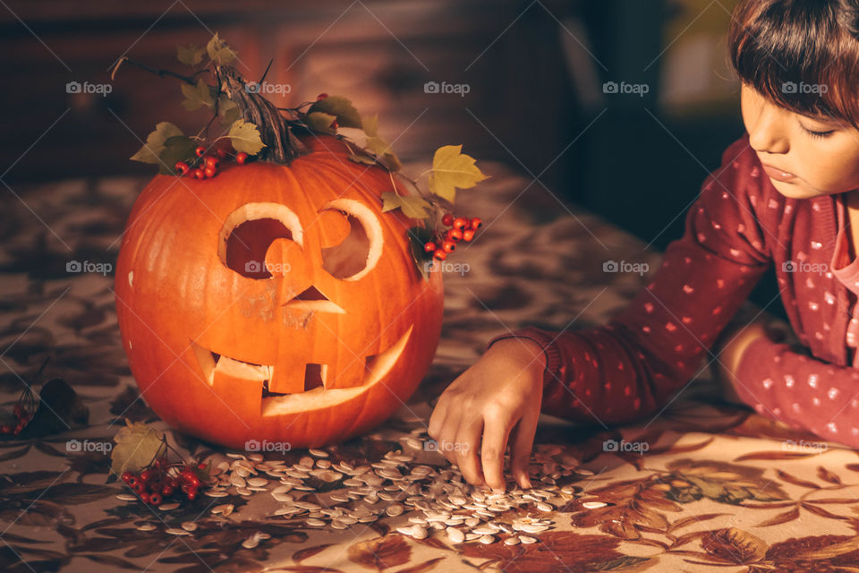 Cute jack-o-lantern, pumpkin seeds, red berries, horse chestnut and a child