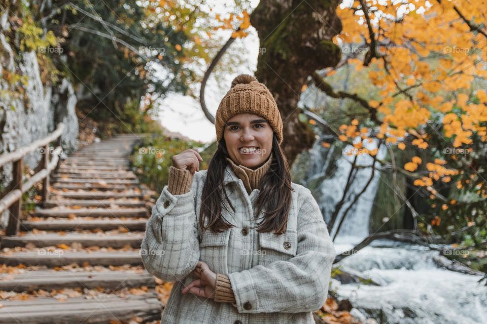 Portrait of happy girl standing on wooden footpath in forest in autumn