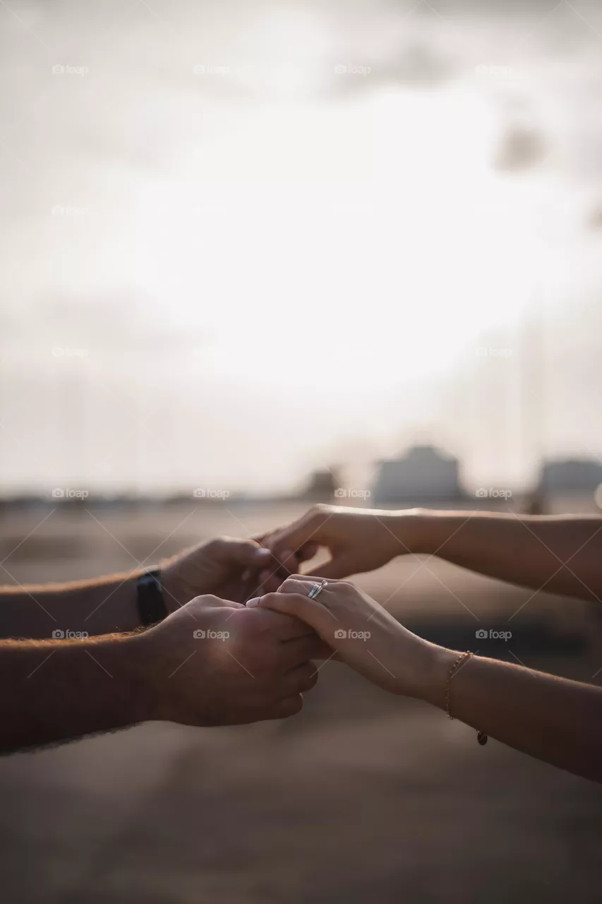 Close up of a couple holding hands on the rooftop of a garage during golden hour for their first anniversary.