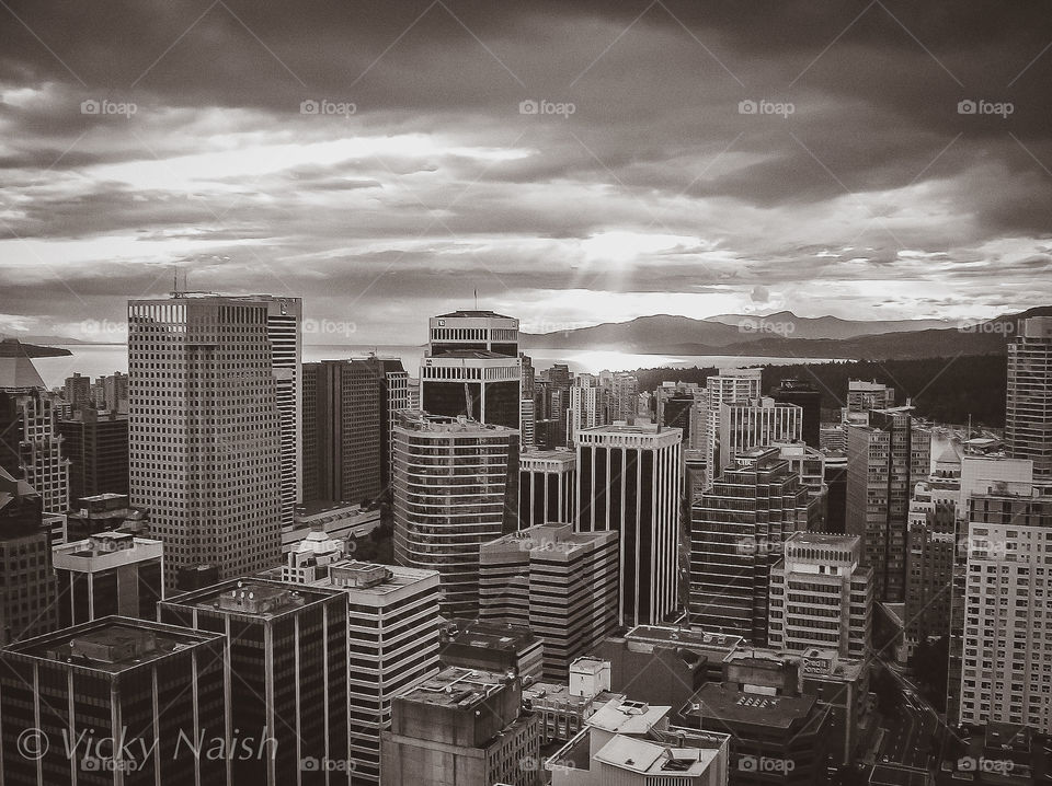 A monochrome shot of the city of Vancouver, British Columbia, Canada. The real beauty of the city lies in the surrounding ocean, mountains & ever-changing sky. The sun’s rays blaze through the clouds to light up Burrard Inlet on the Salish Sea. 🇨🇦