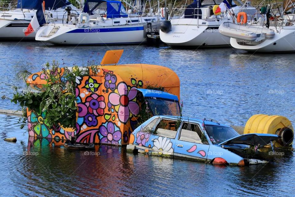 Flower power car and caravan floating in the middle of Vannes' port