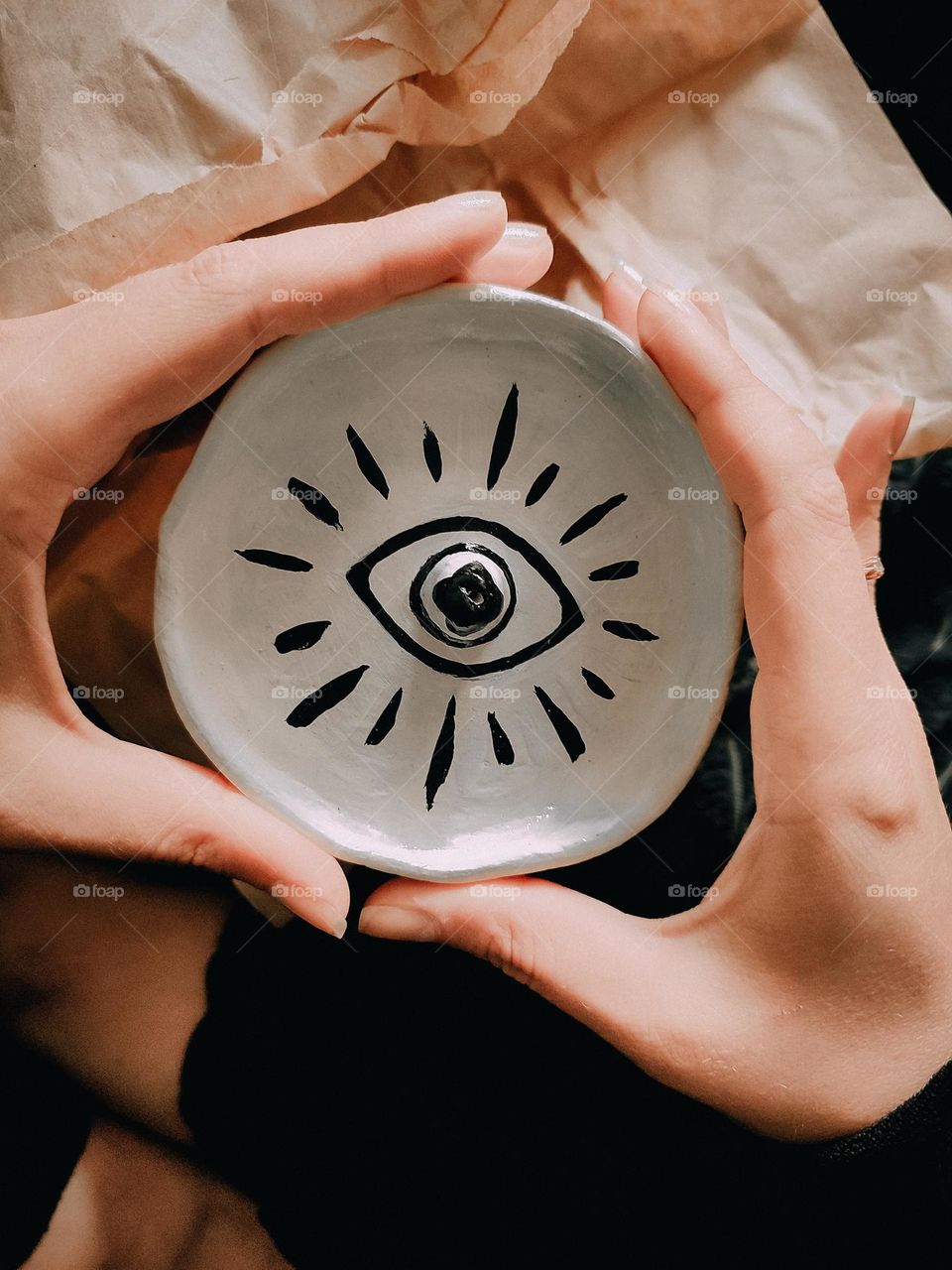 White ceramic plate with eye drawing in hands, meditation pose