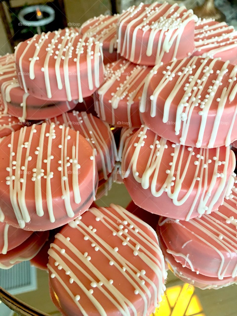 Pink chocolate covered cookies decorated with white chocolate drizzle and sprinkles