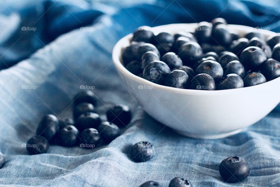Fruits! - Blueberries in a white bowl and scattered on graduated blue fabric  