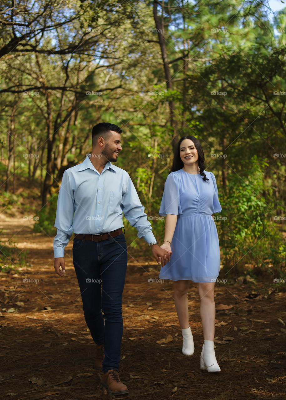 Couples of young people walking in middle of the forest while looking into their eyes, in a sunny day.