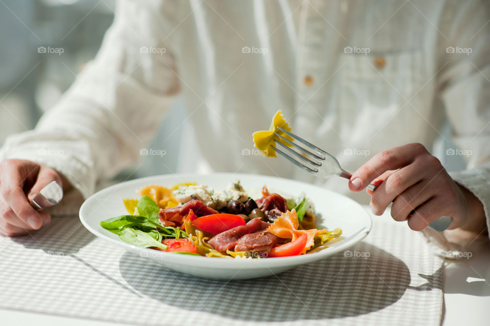 close-up of a young man eating a salad in a light kitchen