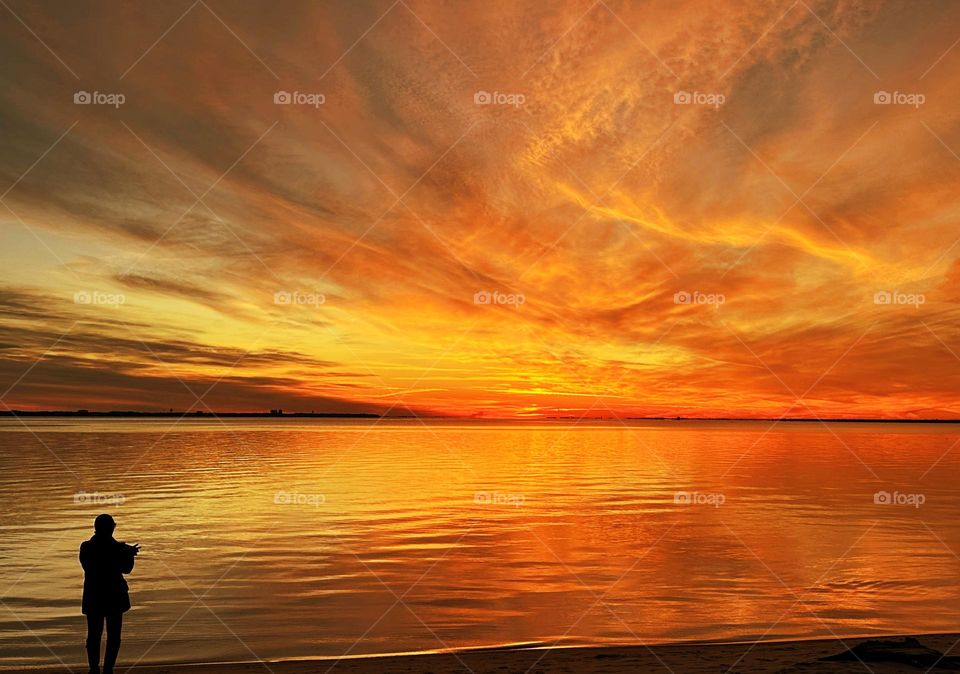 Magic of the Sunset - A young lady photographs sunset. The radiance of the beautIful peach colored sky from the descending sunset was glorious to behold and increasing every moment in splendor. 