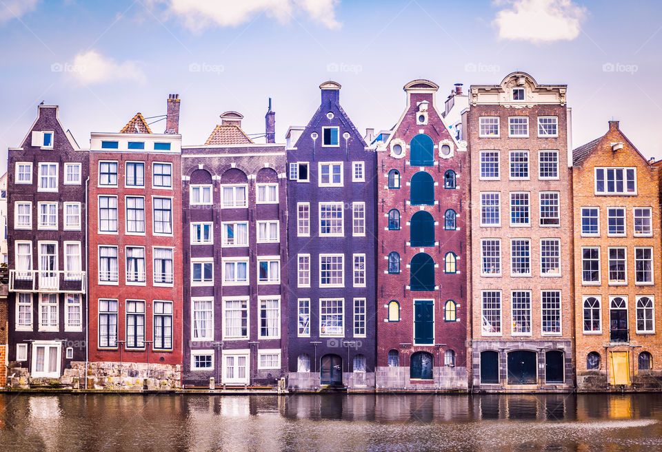 Front view of the colorful typical vintage Amsterdam houses on the Amstel water canal. Historic travel destination.