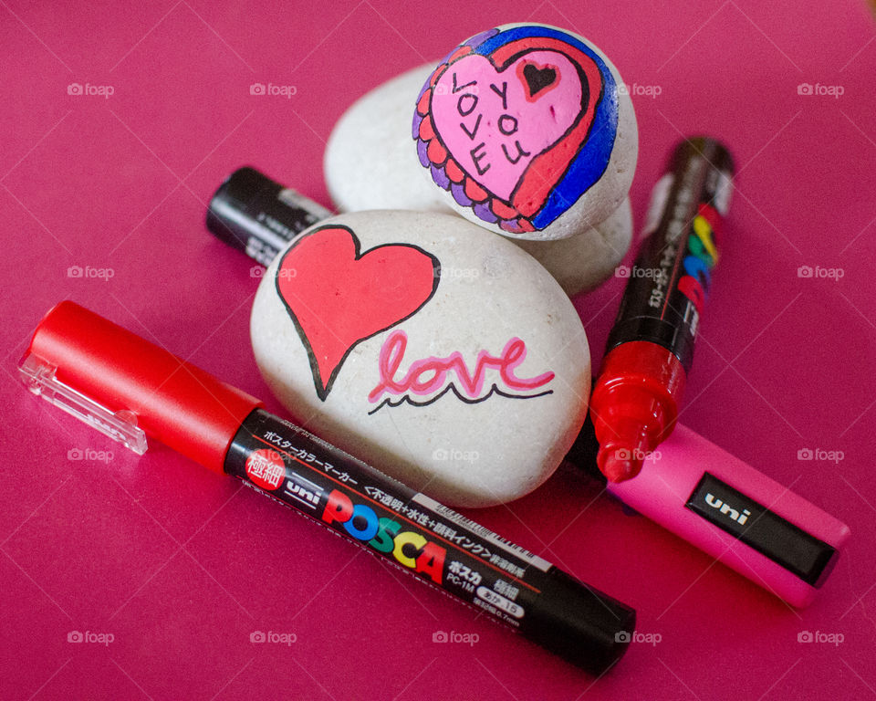 Valentine's Day painted rocks on pink background