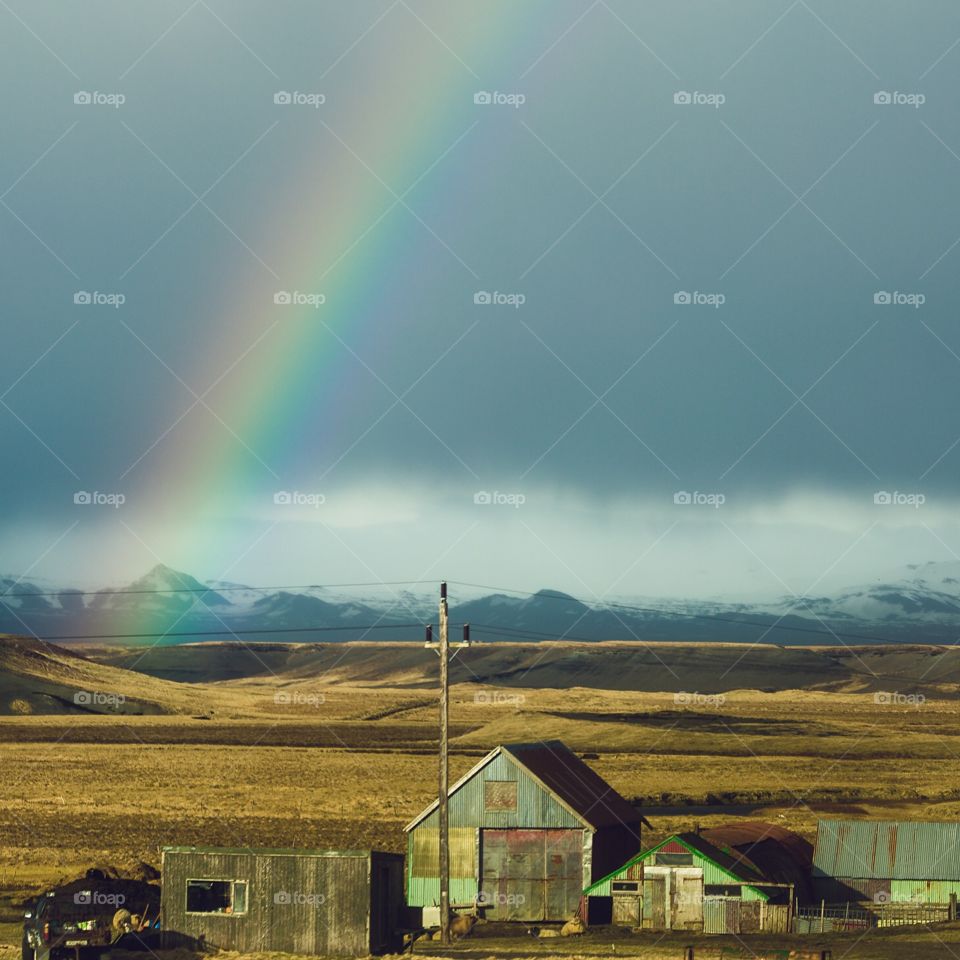 Rainbow over expansive landscape in Iceland. Beautiful rainbow over mountains and barn in Iceland