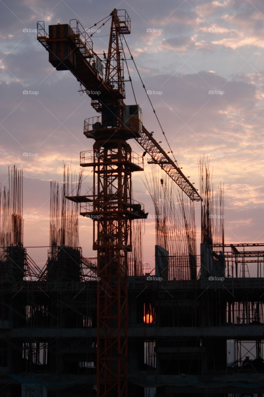 a crane at under construction site at the time of sunrise