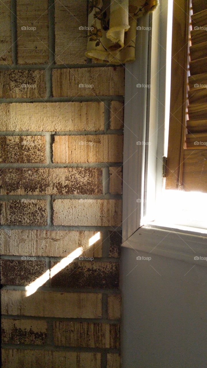 Shaft of sunlight pouring onto fireplace bricks through window.