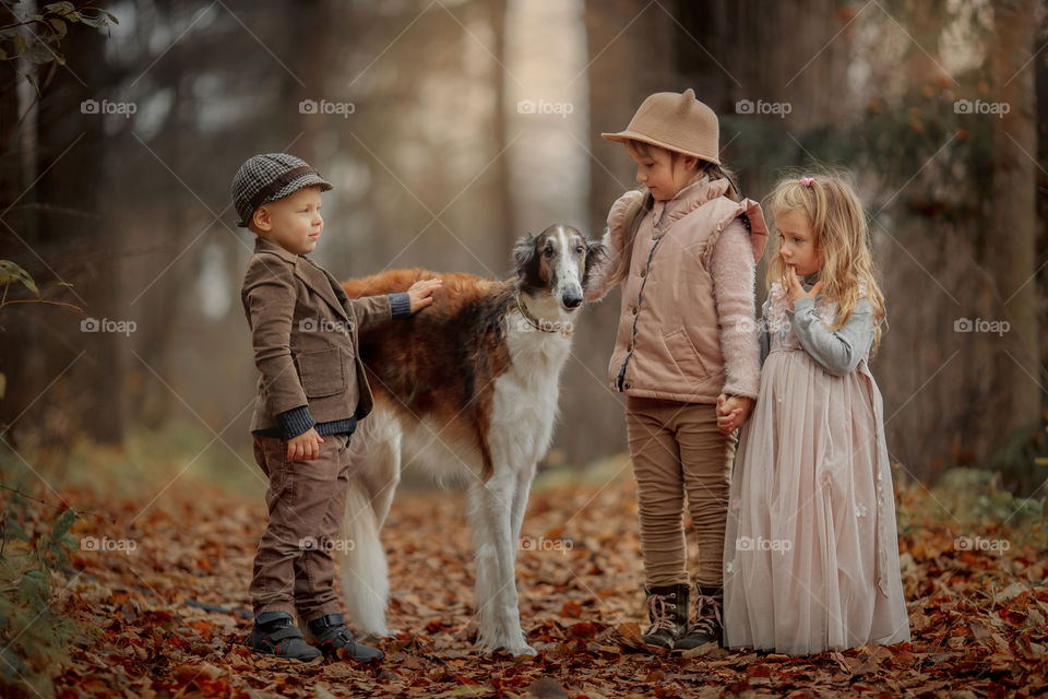 Children with russian borzoi dog in an autumn park 