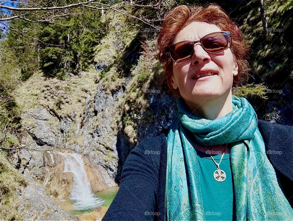 This lovely young lady is enjoying her day trip in the vicinity of „Bayerischzell“, a small town near the Alps in „Bavaria“, Germany visiting a waterfall. 2024. Hypnotic Productions