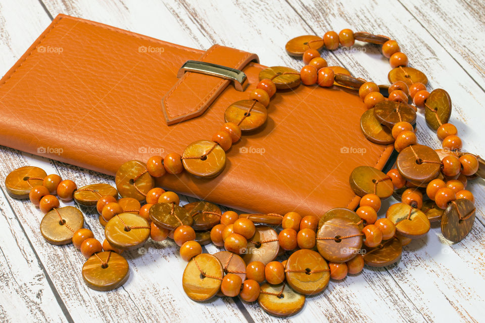 Orange leather wallet and wooden beads.