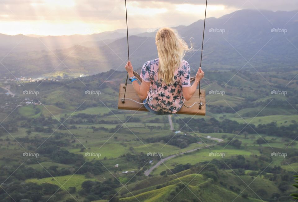 Blonde on a swing on the mountain