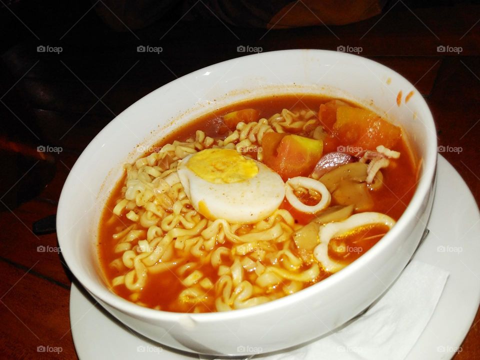 Spicy seafood noodle soup with sliced ​​squid, mushroom and boiled egg on top