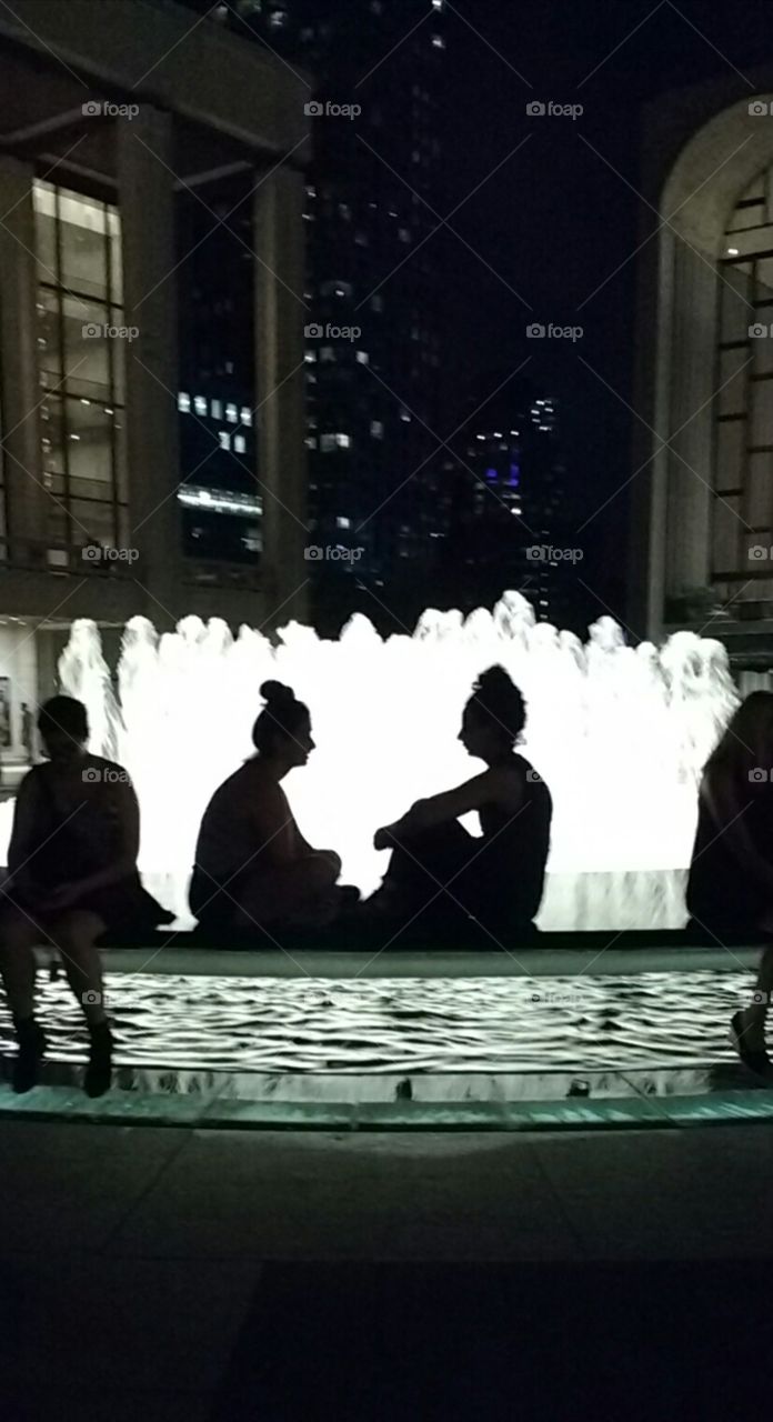 Two Similar Friends Speaking at Fountain in Silhouette