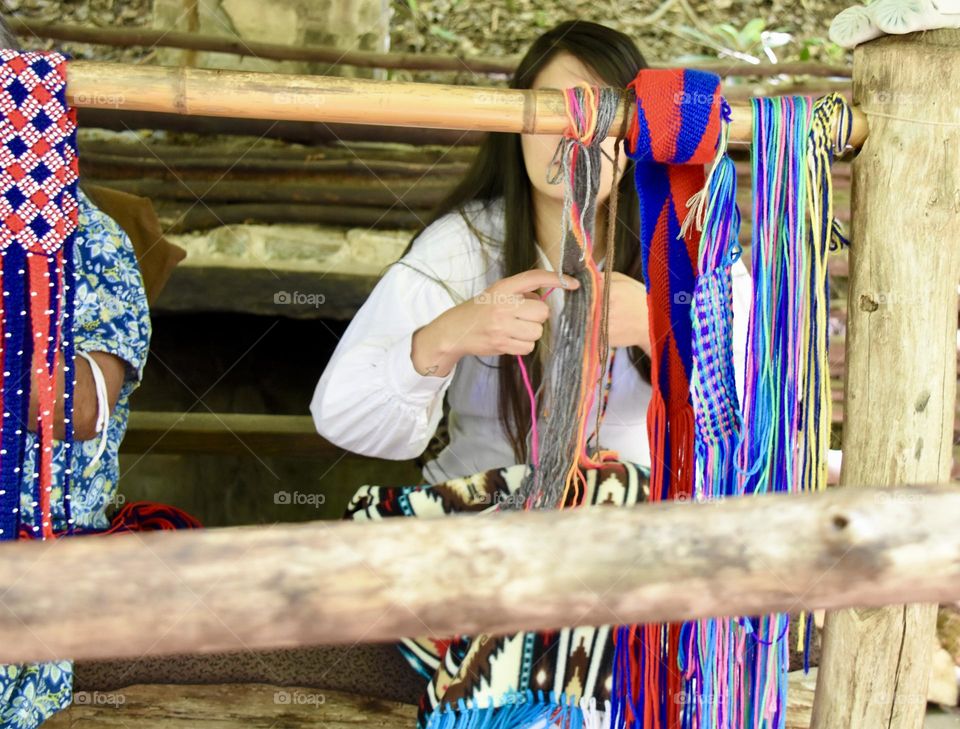 Girl making belts with strips of cloth 