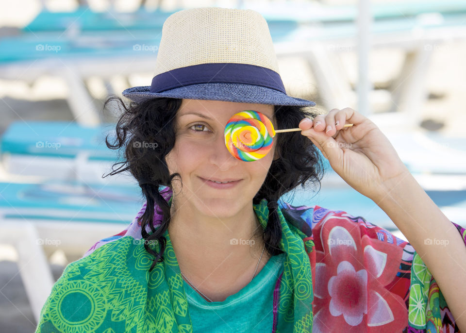 Colorful portrait of young woman with lollipop on the beach, summertime