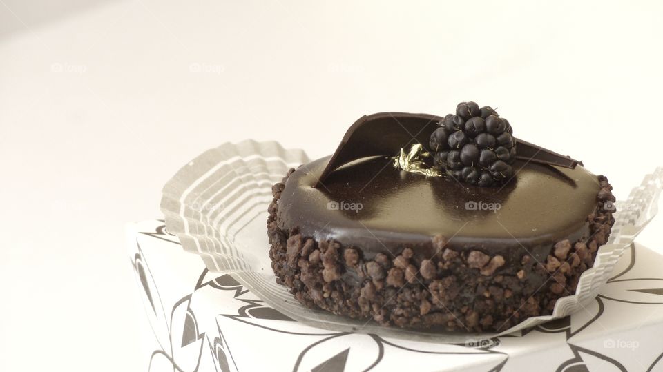 Side view of chocolate delicacy decorated with berry and gold
