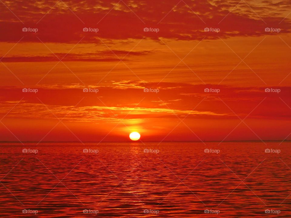 It was sunset. I watched with an unwavering gaze, as a fiery orange orb of light slowly sank beneath the horizon, and threads of light lingered in the sky,
mingling with the clouds