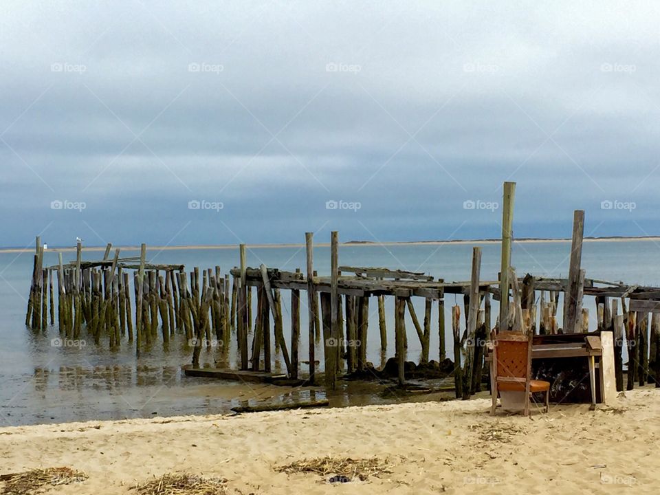 Provincetown beach. Piano stranded on desolate beach near old pier